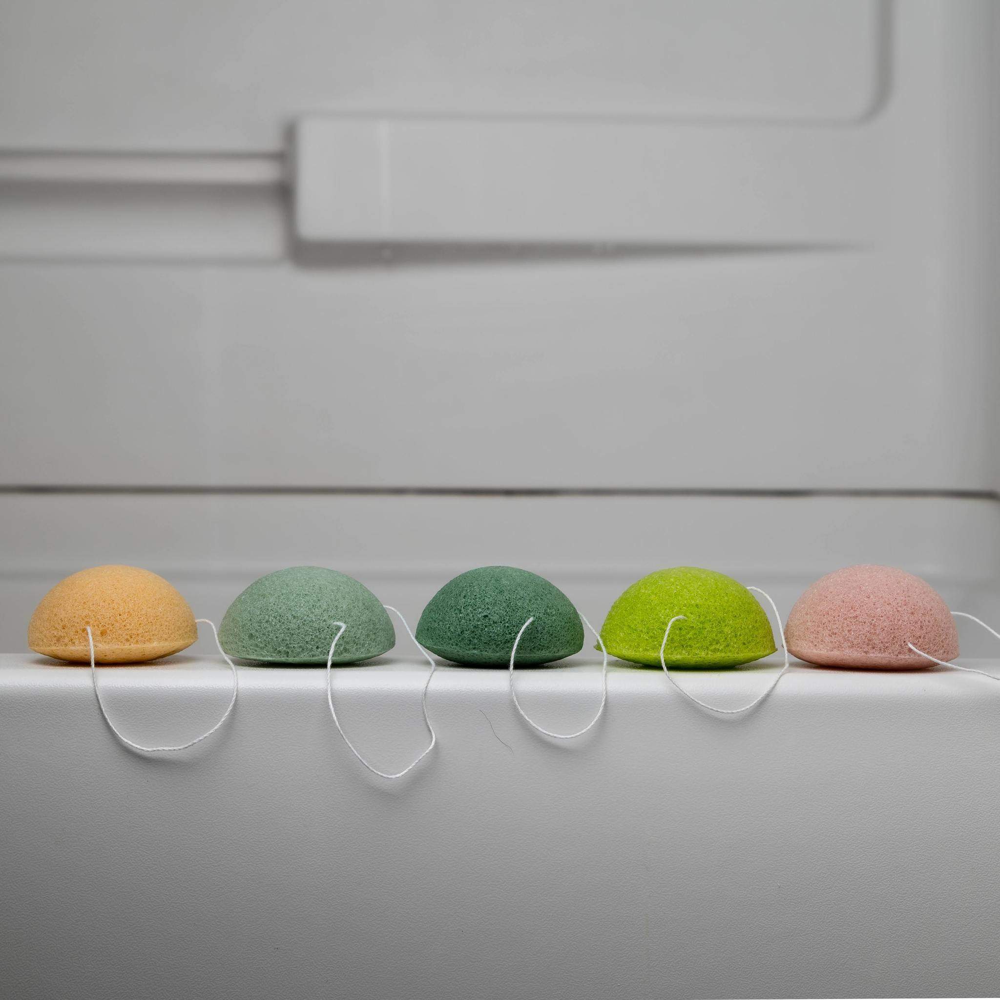 one of each color product lined on edge of bathtub, white color tub