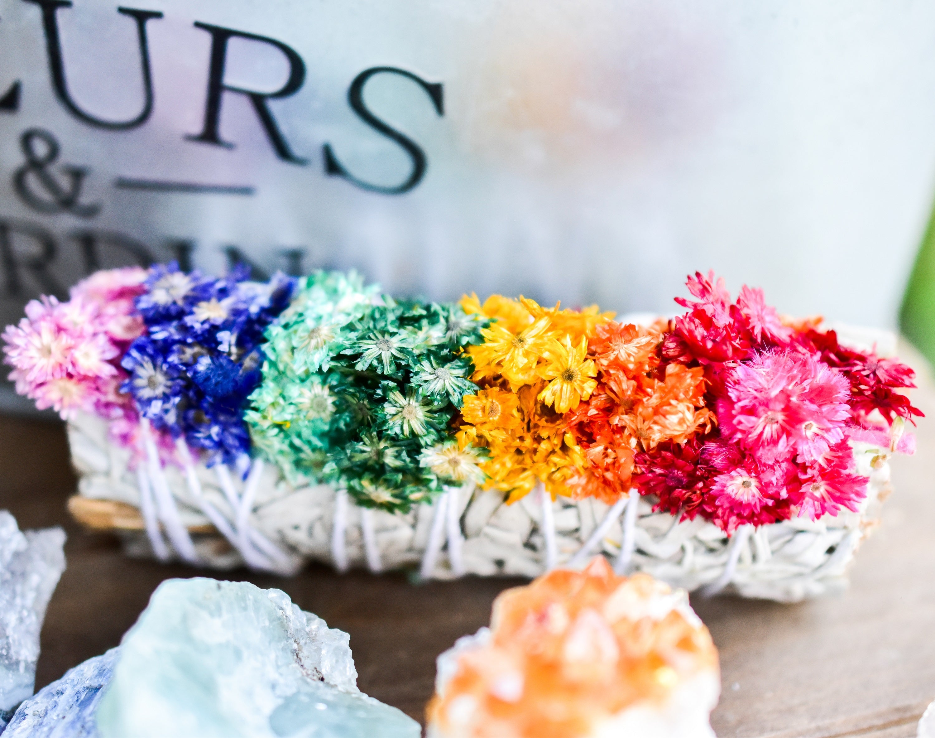 flower adorned sage bundle on a table with sign background