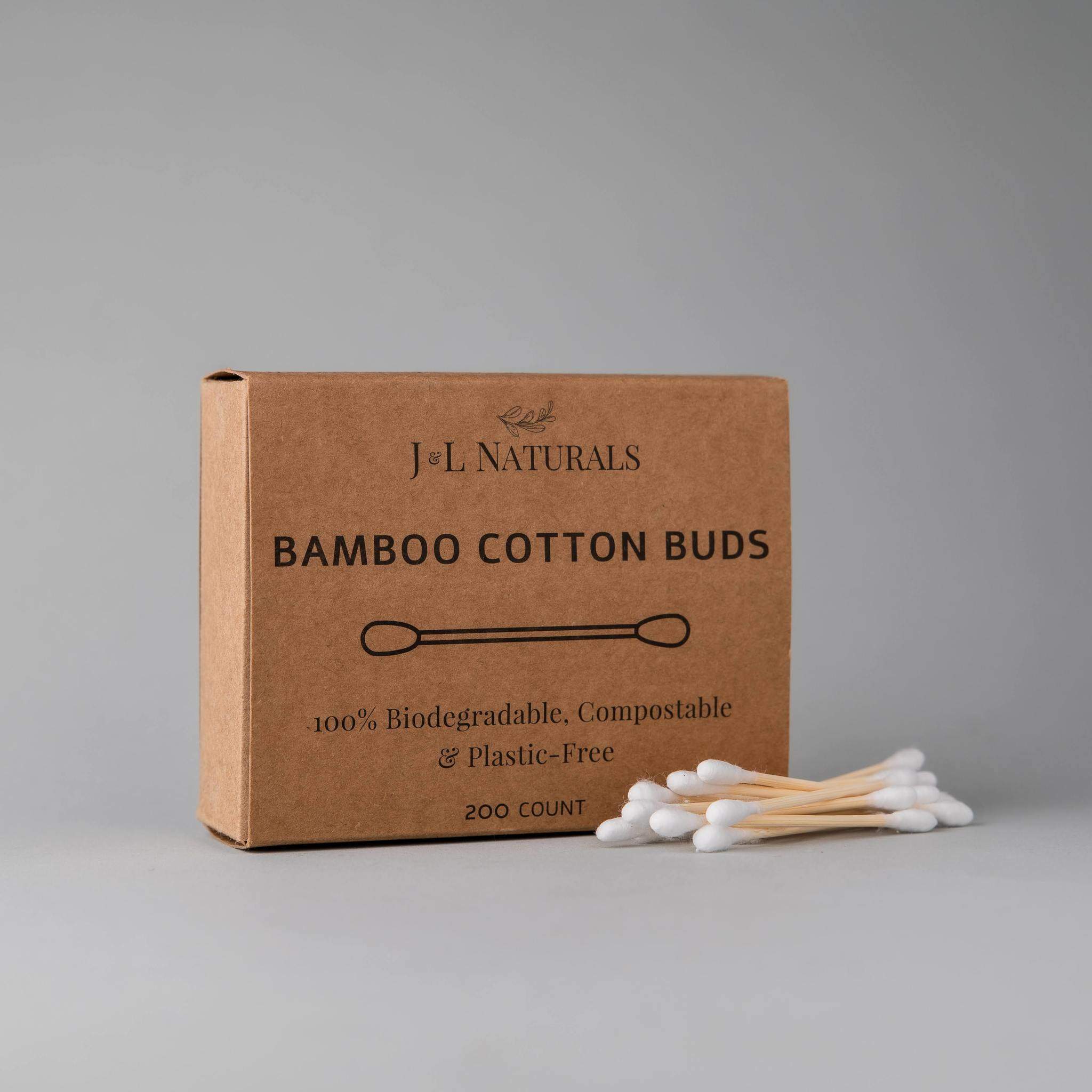 bamboo cotton swabs natural packaging with a stack of swabs next to it and a grey bachground