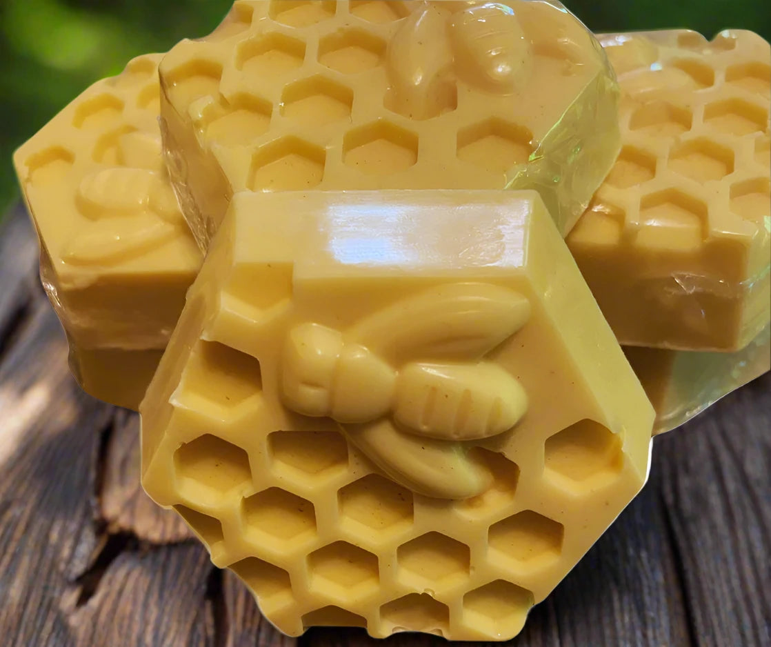 hexagon shaped bar soap with honeycomb cut out and raised honey bee on wooden table and green background