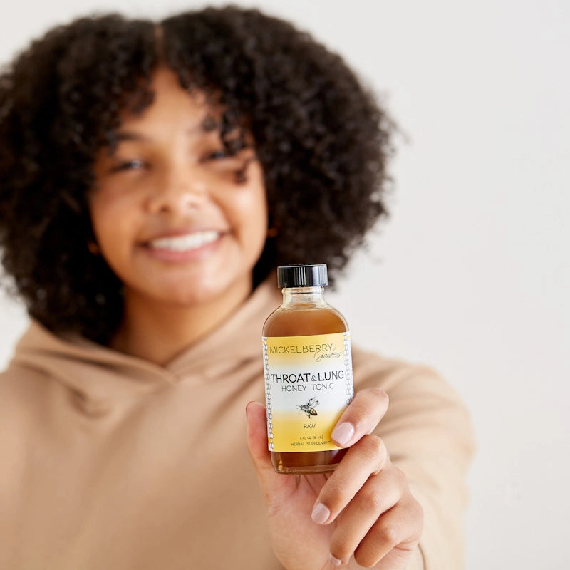 woman holding bottle of tonic and white wall behind her