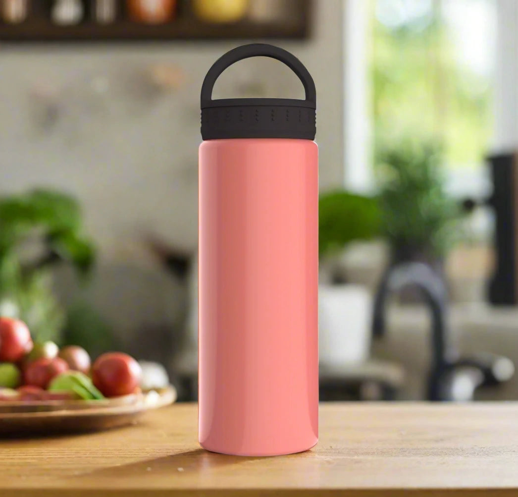 A stylish pink water bottle on a counter, with a tray of food on one side and a kitchen sink on the other.