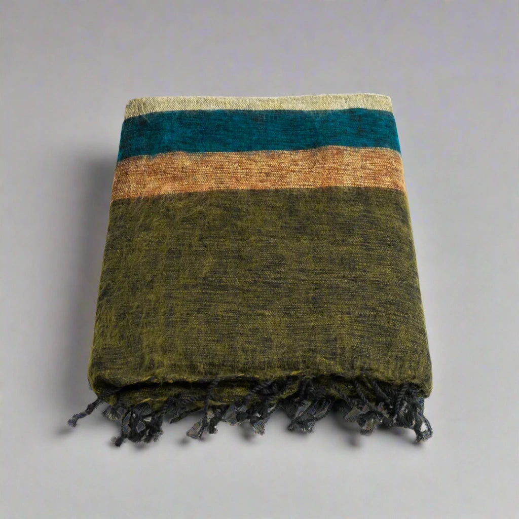 folded yak wool blanket with earth tone stripes and tassels on one side.